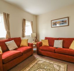 A living room with red sofas and a table at No 8- Farmhouse Retreat in Keswick