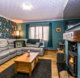 A living room with a sofa, coffee table and fireplace at 36 Cae Rhos in Holyhead