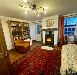 A living room with a bookshelf and fireplace at Penpegws near Aberystwyth