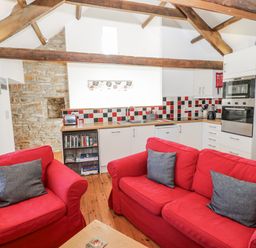 A kitchen with red sofas and a wooden table at Dove Cottage Hexham