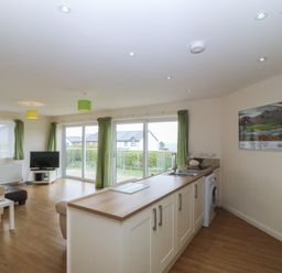 A living room with a kitchen area and a view of the outside at Orme View in Penmaenmawr