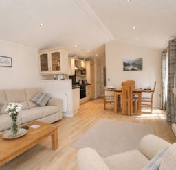 A living room with a sofa and dining area at Tiggywinkle Beck - White Cross Bay Windermere