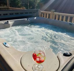 A hot tub with water and a glass of drink at Owls House - White Cross Bay in Windermere