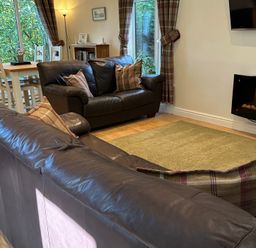 A living room with a sofa and dining area at Owls House - White Cross Bay, Windermere