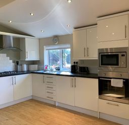 A kitchen with cabinets, stove, oven, and window at Owls House - White Cross Bay Windermere