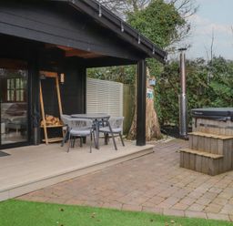 An outdoor seating area with a hot tub at Caban Tan Y Dderwen in Chwilog
