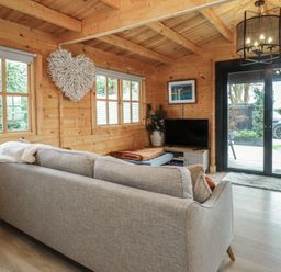 A snug with a sofa, television, and sliding doors at Caban Tan Y Dderwen in Chwilog