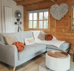 A living room with a sofa and coffee table at Caban Tan Y Dderwen in Chwilog