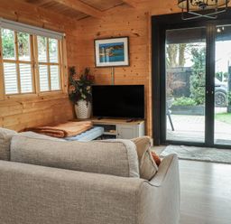 A living room with a sofa and television at Caban Tan Y Dderwen in Chwilog