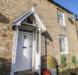 An entrance with a white door and brick wall at Englewood Cottage in Hexham