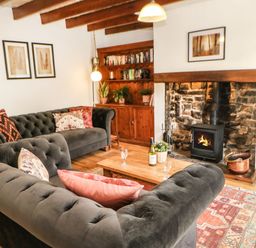 A living room with a sofa, coffee table, and fireplace at Englewood Cottage in Hexham