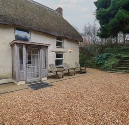 A house with a thatched roof and chairs in front at Plenteth Truro