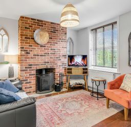 A living room with a fireplace and a television at Bay Tree Cottage in Heacham