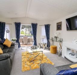 A living room with a sofa and television at 33 Woodpecker Lodge in Llanarth