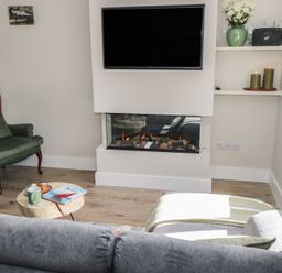 A living room with a fireplace and television at Doire Fhatharta Beag, Carraroe, County Galway