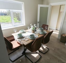 A dining room with a table set for a meal at Doire Fhatharta Beag, Carraroe, County Galway