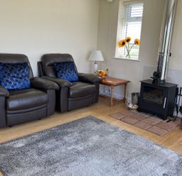 A living room with recliner chairs and a wood burning stove at Seadrift near Happisburgh