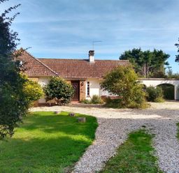 A house with a gravel driveway and greenery at Barton Lodge in Porlock
