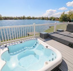 A hot tub on a deck with a view of a lake at Fairways 22 in Tattershall
