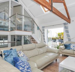 A living room with sofas and a staircase at The Cowshed in Portscatho