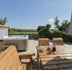 An outdoor area with a hot tub and wooden furniture at Ty Mawr Farm in Llanfairpwllgwyngyll