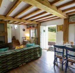 A living room with a sofa and dining area at Cynefin in Newport, Pembrokeshire