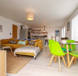 A living room with a yellow sofa and a dining table at La Casita in Newquay