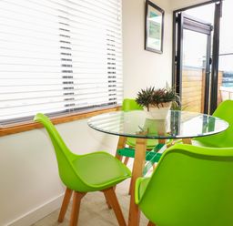 A dining room with glass table and green chairs at La Casita Newquay
