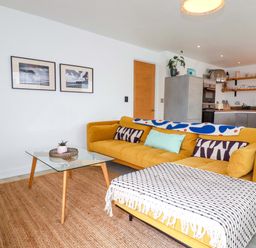 A living room with a yellow sofa and coffee table at La Casita in Newquay