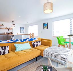 A living room with a sofa and dining area at La Casita in Newquay
