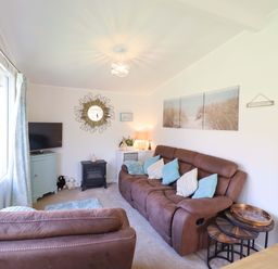 A living room with a sofa and television at Chalet 23 Erw Porthor Tywyn