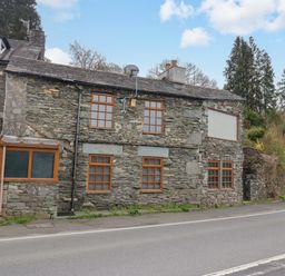 A stone building with windows along the road at Wilders Wood Windermere