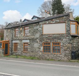 A stone building with windows and a door at Wilders Wood in Windermere