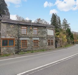A stone building next to a road at Wilders Wood in Windermere