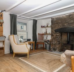 A living room featuring a stone fireplace and wooden furniture at Bedford Cottage in Yelverton
