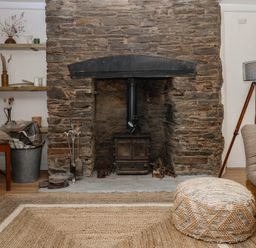 A living room with a stone fireplace and a wood stove at Bedford Cottage in Yelverton