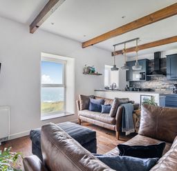 A living room with a television, window and kitchen at Cape View near St Just