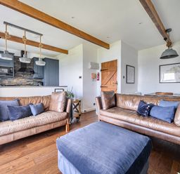 A living room with sofas and a kitchen area at Cape View near St Just