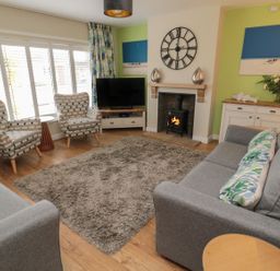 A living room with a sofa, armchairs, and a television at 7 Longstone Close, Chathill