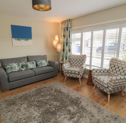 A living room with a sofa, armchairs, and a lamp at 7 Longstone Close Chathill