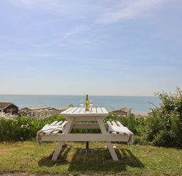 A table with a bottle and glasses overlooking the sea at Salt & Stone Lyme Regis