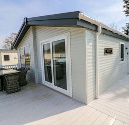 A house with a deck and outdoor furniture at Dukes Meadow in Carmarthen