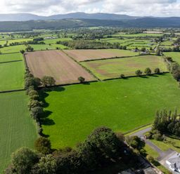 An aerial view of green and brown fields with trees and a road at Ballyneill Farmhouse in Carrick-On-Suir, County Tipperary