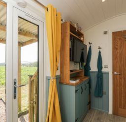 An entryway with a tv and a door at Daisy Shepherd's Hut in South Molton