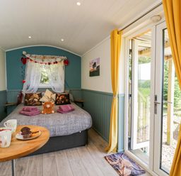 A bedroom with a bed and coffee table at Daisy Shepherd's Hut in South Molton