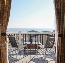 A balcony with chairs and a table overlooking the sea at Bordeaux in Ladram Bay Otterton