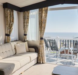 A living room with a sofa and a view of the sea at Bordeaux in Ladram Bay Otterton