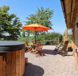 An outdoor space with a hot tub and seating area at Nelli Lodge at Mile End, Crediton