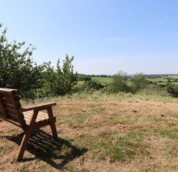 A bench with a view of fields and trees at Nelli Lodge at Mile End Crediton