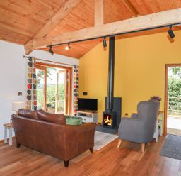 A living room with a fireplace and sofa at Nelli Lodge at Mile End, Crediton